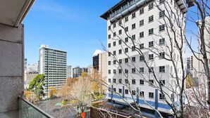 A high-rise building with multiple windows and balconies, surrounded by other tall buildings and trees. - Central Modern Apt. w/ Working Space Zodiak Stays (Auckland)