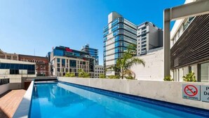A swimming pool with a 'No Diving' sign, surrounded by modern buildings.