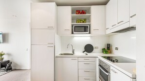 A modern kitchen with white cabinetry, a built-in microwave, and a stove.