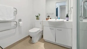 A modern bathroom with a toilet, sink, and glass shower enclosure.