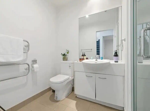 A modern bathroom with a toilet, sink, and glass shower enclosure.