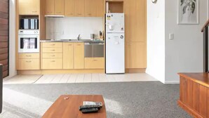 A compact kitchen with wooden cabinets, a white refrigerator, and a built-in oven.