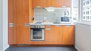 Una cocina moderna con armarios de madera, horno integrado, microondas y ventana con vista a la ciudad.