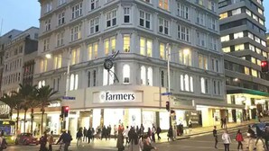 Un edificio de varios pisos con un llamativo letrero de 'Farmers' a nivel de calle.