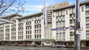 A large building with a modern architectural style, featuring a prominent entrance with a glass canopy. - Stylish Studio With Pool And Gym (Auckland)