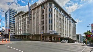Un grand hôtel à plusieurs étages, doté d’une architecture moderne, qui se distingue par son entrée d’angle imposante et sa vaste façade vitrée.