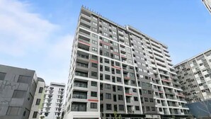 A modern high-rise building with multiple balconies and a flat roof terrace. - Beautifully Modern Brand New Central Apartment (Auckland)