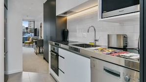 A modern kitchen with white cabinets, a Bosch dishwasher, a Panasonic microwave, and a toaster. - Beautifully Modern Brand New Central Apartment (Auckland)