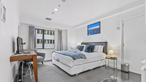 A modern bedroom with a bed, desk, and chair, a window with curtains, and a painting on the wall.