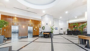 A spacious lobby with a reception desk, seating area, and elevators.