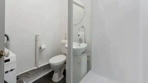Ein kleines, weißes Badezimmer mit Toilette, Waschbecken und Spiegel.