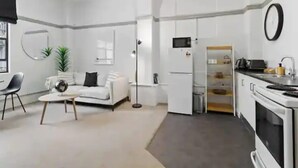 Ein stilvolles, weißes Wohnzimmer mit einer Couch, einem Couchtisch und einem Essbereich.