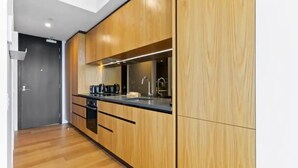 Une cuisine moderne avec des meubles en bois, un plan de travail noir et un four encastré.