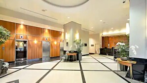 A spacious lobby with a central seating area, a reception desk, and a large potted plant. - Pool, Gym And Style In The Cbd (Auckland)