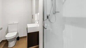 A modern bathroom with a toilet, sink, and shower. - Stylish Central City 1-Bedroom With Patio (Auckland)