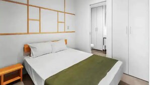 A bedroom with a bed, a nightstand, a wardrobe, and a wall with a geometric design. - Stylish Central City 1-Bedroom With Patio (Auckland)