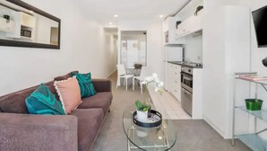 A modern apartment with a living room, kitchenette, and dining area.