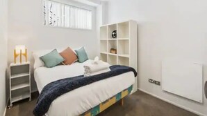 A modern bedroom with a bed, bedside tables, a wardrobe, and a window.