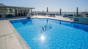 En pool på taket med fri utsikt över stadens silhuett, inklusive ett högt torn.