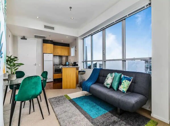 Un appartement moderne doté d’une cuisine, d’un coin repas et d’une grande fenêtre offrant une vue sur la ville.