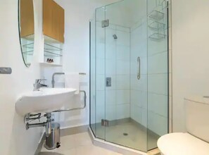 Une salle de bain moderne avec une douche à parois de verre, un lavabo blanc et des toilettes.