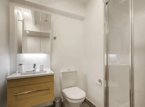 A bathroom with a toilet, a sink, a mirror, and a shower. - Condo in Queen St CBD w Pool and Gym Zodiak Stays (Auckland)