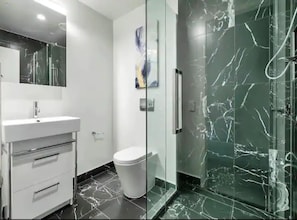 A modern bathroom with a white vanity, a toilet, and a glass-enclosed shower area. - Stylish 2-Storey Retreat With Parking Zodiak Stays (Auckland)
