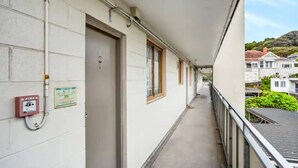 A narrow corridor with doors, a fire alarm, and a view of houses in the background.