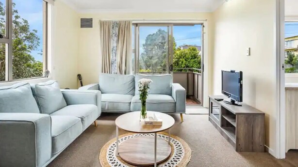 A modern living room with a sofa, a coffee table, and a TV.