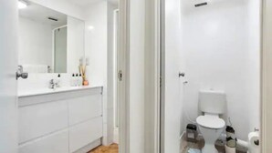 A modern bathroom with a white sink, mirror, and toilet.