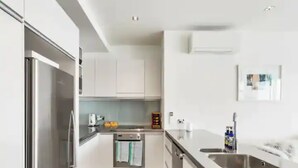 Een moderne keuken met roestvrijstalen apparatuur, witte kasten en een groot keukenblok met een spoelbak.
