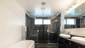 A modern bathroom with a large bathtub, a glass shower enclosure, and a vanity with a mirror. - North Shore Mansion With 20M Pool (Auckland)