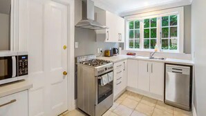 Una cocina moderna con armarios blancos, estufa a gas, microondas y lavavajillas.