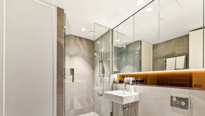 Une salle de bain moderne avec une douche à parois de verre, un lavabo blanc et des toilettes.