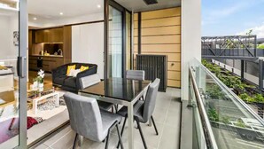 Un appartement moderne comprenant un coin repas, une cuisine et un balcon offrant une vue sur la ville.