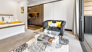 Un salon moderne avec un canapé, une table basse en verre et une vue sur la cuisine.