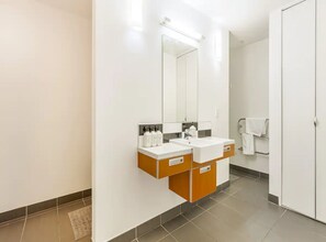 Ein modernes Badezimmer mit einem weißen Waschbecken, einem Spiegel und zwei Holzschränken.