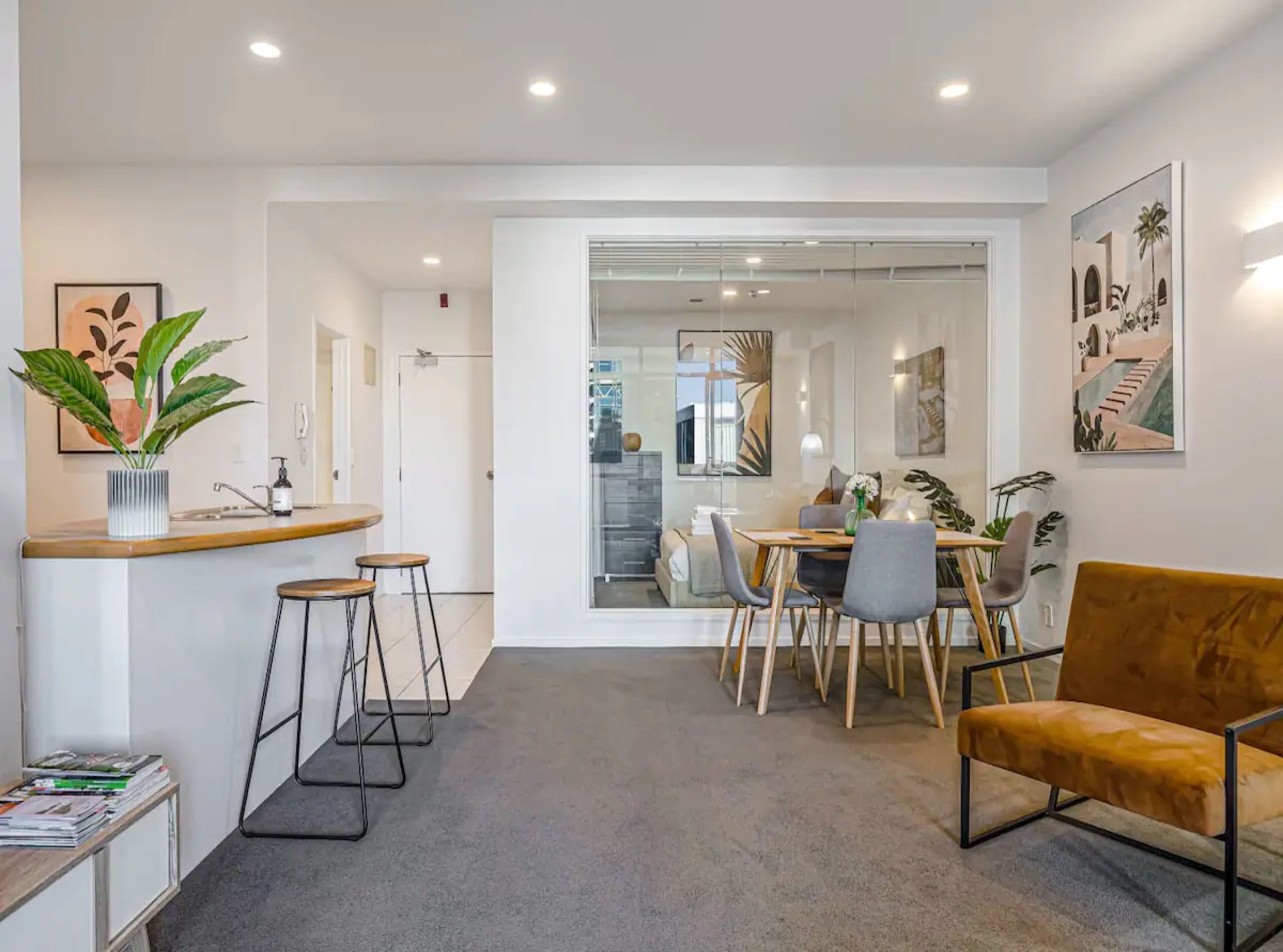 A modern kitchen with a bar area, dining space, and a sofa.