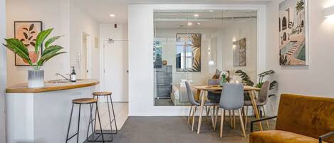 A modern kitchen with a bar area, dining space, and a sofa.