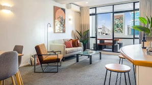 Una sala moderna con sofá, sillones, una mesa de centro y un comedor con barra.