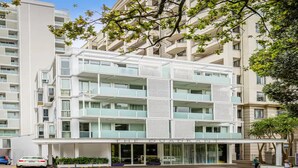 A multi-story hotel with a modern architectural design, featuring balconies and large windows. - Tidy Apartment With Balcony (Auckland)