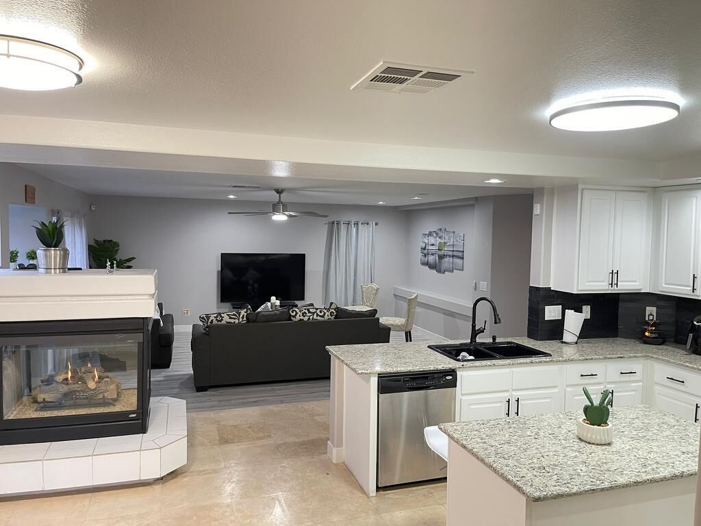 A modern kitchen with white cabinets, a built-in dishwasher, and a granite countertop.