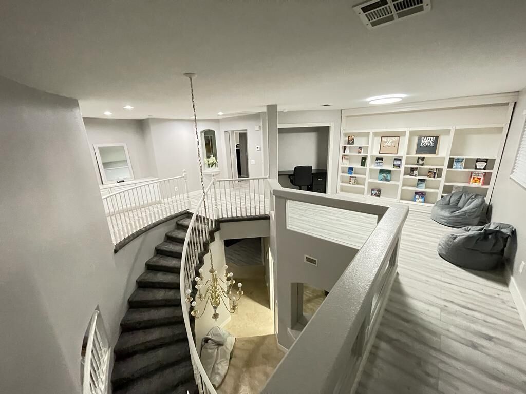 Un intérieur à plusieurs niveaux comprenant un escalier, un coin lecture avec des étagères et un espace détente avec des fauteuils en forme de sac.
