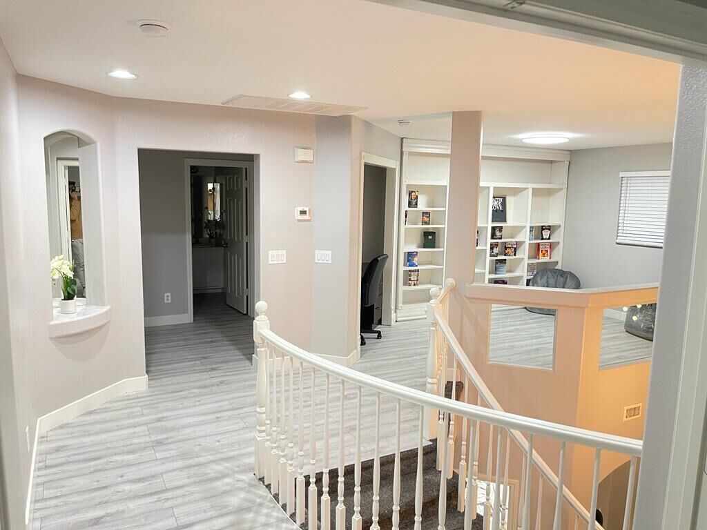 A multi-level interior with a staircase, a bookshelf, and a small seating area.
