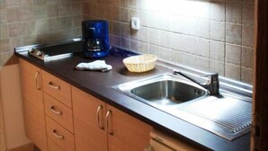 Une cuisine compacte avec des meubles en bois, un évier en acier inoxydable et une machine à café.