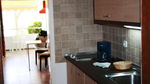 Une cuisine avec un plan de travail foncé, une machine à café, un évier et une fenêtre donnant sur l’extérieur.