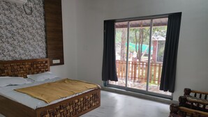 Un dormitorio con una cama de madera, vistas al exterior a través de un ventanal grande y un banco de madera junto a la ventana.