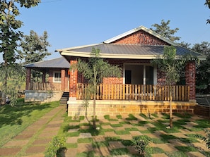 A brick house with a porch, a small garden, and a paved walkway. - Brick Villa (Karjat)