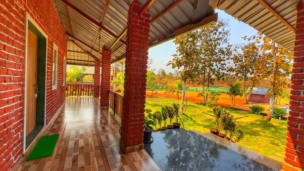 Un balcón techado con vistas a un jardín ajardinado y una piscina.