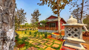 Una casa de ladrillo rojo con un patio empedrado y una estructura decorativa blanca.